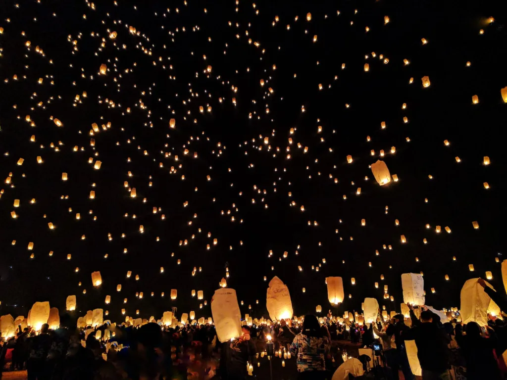 groupe de personnes jetant des lanternes en papier sur le ciel pendant la nuit